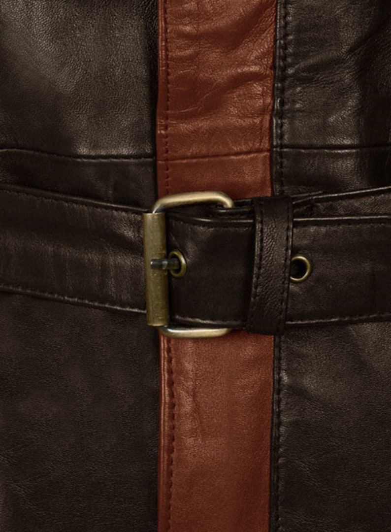 May include: A brown leather jacket with a brown leather belt and a brown leather buckle. The jacket has a vertical stripe of a lighter brown leather down the front.