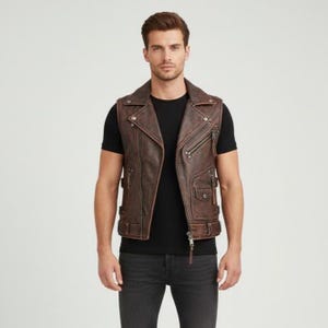 May include: A brown leather vest with a classic biker jacket design. The vest features a notched collar, asymmetrical zipper closure, multiple pockets, and decorative stitching. The vest is worn over a black t-shirt and paired with dark gray jeans.