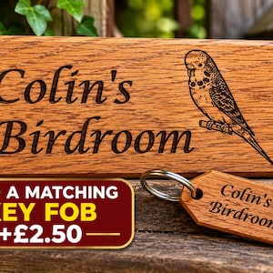 May include: A rectangular wooden sign with the engraved text Colin's Birdroom and a detailed illustration of a budgerigar. Beside it lies a matching wooden key fob featuring the same text and bird graphic attached to a silver metal ring.