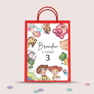 Può includere: Borsa regalo rossa con personaggi di Toy Story. La borsa ha manici rossi e un design rettangolare con la scritta "Brandon is turning 3".