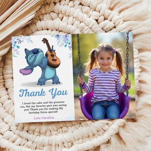 May include: A personalized thank you card featuring a cartoon character holding a ukulele and a photo of a girl on a swing. The card has the words "Thank You" in blue script and a message thanking someone for making a birthday special.