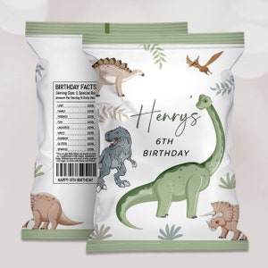 Op de afbeelding: Een witte chipzak met een groene rand en illustraties van dinosaurussen. De zak heeft de tekst "Henrys 6TH BIRTHDAY" en "HAPPY 6TH BIRTHDAY".