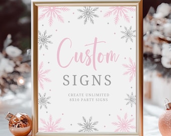 May include: A gold-framed sign with a white background and pink and silver snowflakes. The sign says "Custom Signs" and "Create Unlimited 8x10 Party Signs".