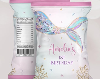 May include: White and pink birthday party favor bags with a mermaid tail design. The bags have the text "Amelia's 1st Birthday" and "Birthday Facts" with a list of positive attributes. The bags are decorated with stars and coral.