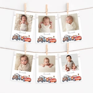 May include: Six baby milestone photo cards, each clipped to a string with wooden pegs. Each card shows a baby photo and a watercolour illustration of Cars characters, with text indicating the month.