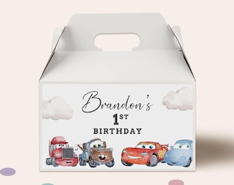 Op de afbeelding: Witte cadeauverpakking met handvat, versierd met de tekst "Brandon's 1st Birthday" en cartoonauto-illustraties. De doos is versierd met wolken. De auto's zijn onder meer een rode vrachtwagen, een bruine sleepwagen, een rode raceauto en een blauwe auto.