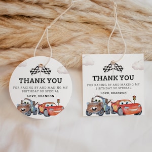 Pode incluir: Duas etiquetas de presente brancas com o texto "OBRIGADO" e uma mensagem de aniversário. As etiquetas apresentam ilustrações de carros de desenho animado, bandeiras quadriculadas e nuvens. Uma etiqueta é redonda, a outra quadrada.