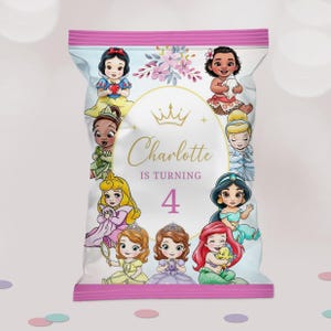 May include: A pink and white party favor bag featuring cartoon princesses. The bag has the text "Charlotte is turning 4" in gold script. The princesses include Snow White, Ariel, and Jasmine.