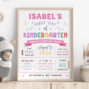 Puede incluir: Un cartel imprimible colorido para el primer día de jardín de infantes de un niño. El cartel presenta el nombre "Isabel's" en rosa, las palabras "First Day of Kindergarten" en colores arcoíris y la fecha "August 15, 2025". El cartel también incluye información sobre la edad del niño, su altura, sus cosas favoritas y sus aspiraciones profesionales futuras.