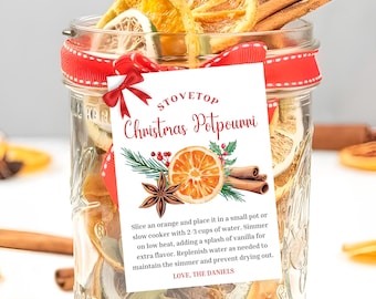 May include: A glass jar filled with dried orange slices, cinnamon sticks, star anise, and other spices. A white tag with red text reads "Stovetop Christmas Potpourri" and includes instructions for making the potpourri.