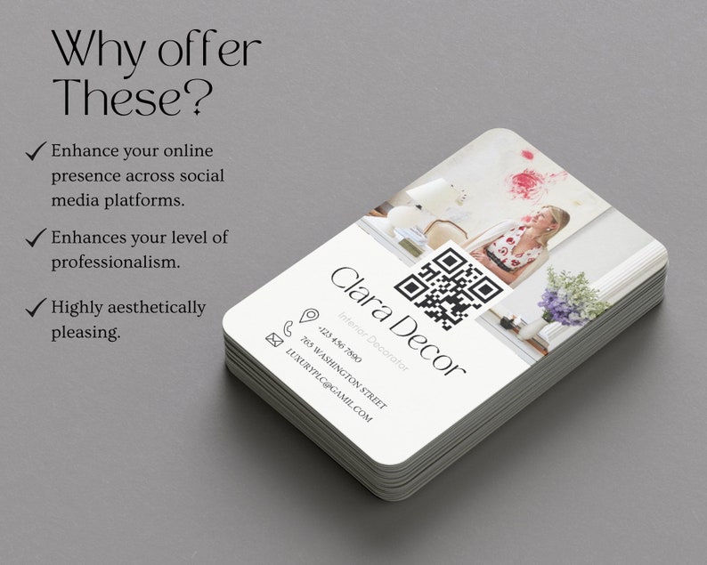May include: A stack of white business cards with rounded corners. The top card features a black and white QR code, the text "Clara Decor", and the words "Interior Decorator". The card also includes a phone number, address, and email address. The background of the card is a blurry image of a woman standing in a room.