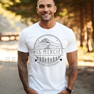 Könnte beinhalten: Weißes T-Shirt mit einem schwarz-weißen Grafikdesign, das eine Bergkette, Bäume und den Text "HIS MERCIES ARE NEW EVERY MORNING" mit dem Schriftzitat "LAMENTATIONS 3:23" zeigt.