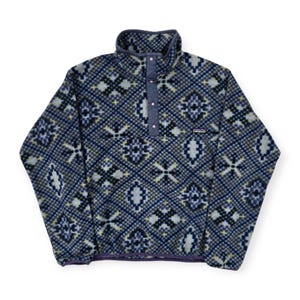 May include: A blue fleece pullover with a geometric pattern in shades of blue, gray, and yellow. The pullover has a stand-up collar, a button placket, and a small logo patch. The hem and collar are trimmed in purple.