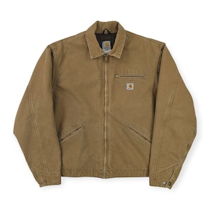 May include: A brown Carhartt jacket with a full zip, collar, and multiple pockets. The jacket has the Carhartt logo on the chest and a small zipped pocket. Made from a durable, workwear-style material. The jacket is a classic workwear style.