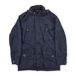 May include: A dark navy blue field jacket featuring a high collar, a front zipper closure with a snap-button placket, four large front pockets with buttoned flaps, shoulder epaulets, and adjustable buttoned cuffs on the long sleeves.