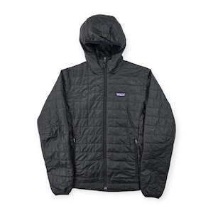May include: A black quilted hooded jacket with a full-length front zip, long sleeves, and two zipped side pockets. The Patagonia brand logo is visible on the left chest area. The garment features a grid-like stitched pattern throughout.