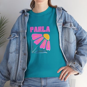 May include: A teal blue t-shirt with a pink and yellow flower graphic and the word "PARLA" in pink letters.