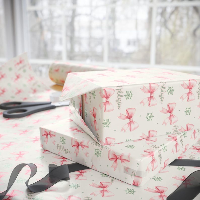 A wrapped box and a partially unwrapped roll of patterned gift paper lie on a table with scissors and ribbon.