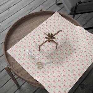 A large sheet of patterned wrapping paper with pink bows is laid out on a round wooden tray.