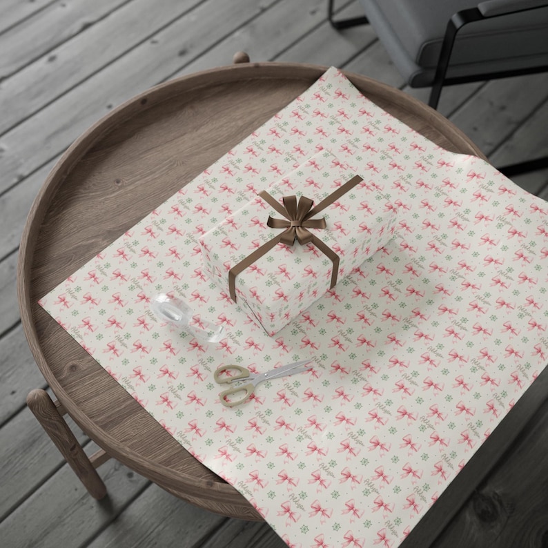 A large sheet of patterned wrapping paper with pink bows is laid out on a round wooden tray.
