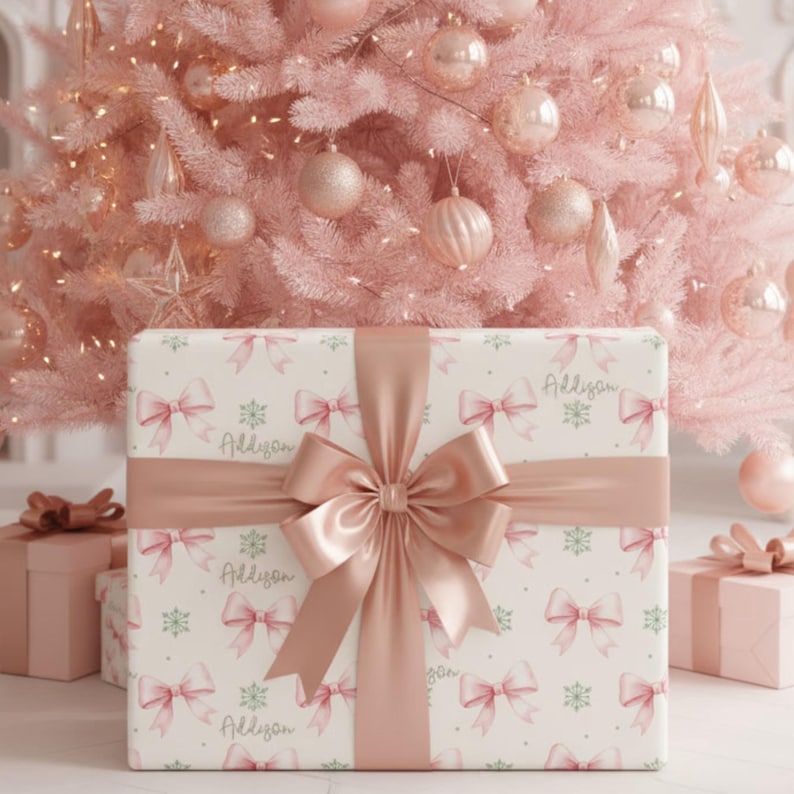 A gift wrapped in custom pink bow and snowflake paper is displayed in front of a pink Christmas tree with ornaments.