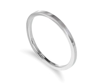 Può includere: Un anello d'argento dal design minimalista. L'anello è una fascia sottile con una parte superiore leggermente arrotondata e una finitura liscia e lucida. L'anello è posto su uno sfondo bianco.
