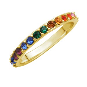 May include: A gold ring with a band of colorful gemstones. The gemstones are arranged in a rainbow pattern, with colors including red, orange, yellow, green, blue, and purple. The ring is set against a white background.