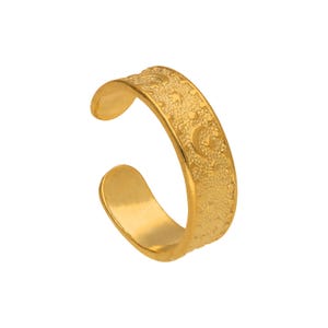 May include: A gold-coloured toe ring with a textured surface and crescent moon designs. The open-ended ring is made of a shiny, metallic material. The ring is designed to be worn on the toe.