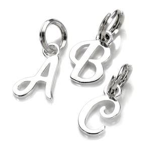 May include: Three silver letter charms spelling out A, B, and C. Each charm is in a cursive font and has a small loop at the top for attaching to a necklace or bracelet. The charms are set against a white backdrop.
