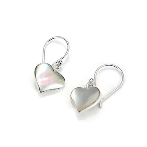 May include: A pair of heart-shaped earrings with a pearlescent finish. The earrings have a silver-coloured hook design. The heart-shaped pendants have a subtle pink and white iridescence, creating a delicate and romantic aesthetic.