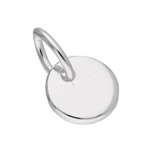Peut inclure: Un petit pendentif argenté avec un charm circulaire et une boucle pour l'attacher. Le charm est lisse et réfléchissant, captant la lumière. Le pendentif est probablement en argent sterling ou en métal similaire.
