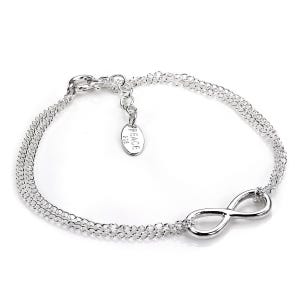 Op de afbeelding: Een zilverkleurige armband met een dubbel kettingontwerp. De armband heeft een oneindigheidssymbool en een klein label met de tekst "PEACE 925". De armband is waarschijnlijk gemaakt van sterling zilver en is ontworpen voor dagelijks gebruik.