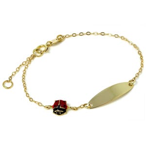 May include: A gold bracelet featuring a ladybird charm and a blank oval tag. The ladybird is red with black spots and a black head. The bracelet has a delicate chain and a clasp for closure.