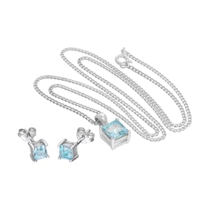 May include: A silver necklace with a square, pale blue gemstone pendant and matching stud earrings. The chain is delicate, and the earrings and pendant have a simple, elegant design. The jewellery set is displayed on a white background.