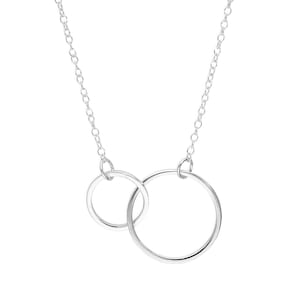 May include: A silver necklace with two linked circles. The circles are suspended from a fine chain. The design is simple and elegant, suitable for everyday wear. The necklace is made of a shiny metal.