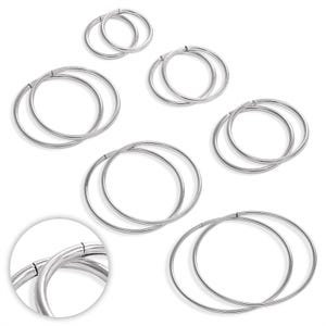May include: A collection of silver-colored hoop earrings of varying sizes, displayed against a white background. The earrings are round and appear to be made of metal. A close-up shows the clasp detail. The image showcases jewelry.