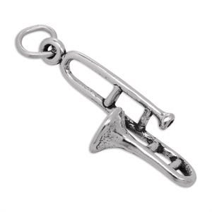 Op de afbeelding: Een zilverkleurige metalen bedel in de vorm van een trombone muziekinstrument. De bedel is voorzien van een gedetailleerde schuif, beker en mondstuk, met een kleine ronde ring aan de bovenkant om aan een ketting of armband te bevestigen.