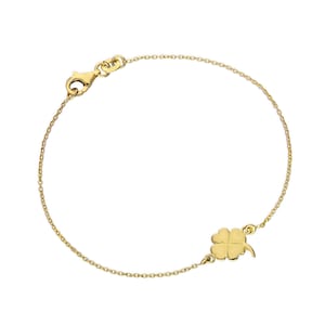 Pode incluir: Uma delicada pulseira dourada com um berloque de trevo de quatro folhas. A pulseira tem uma corrente fina e um fecho lagosta. O trevo é um símbolo de boa sorte.