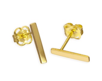 May include: A pair of gold-colored bar stud earrings. Each earring features a small, rectangular bar design. The earrings have a post and butterfly backing for secure wear. The earrings are set against a white background.