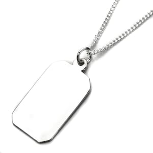 Op de afbeelding: Een zilverkleurige hondenpenning hanger met een gepolijste afwerking, hangend aan een bijpassende ketting. De penning heeft een rechthoekige vorm met licht schuine randen en een kleine lus aan de bovenkant voor de ketting. De ketting is een curb-stijl.