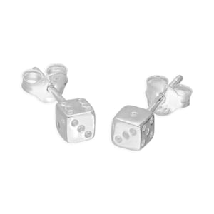 Könnte beinhalten: Ein Paar silberfarbene Würfel-Ohrstecker. Jeder Ohrring ist ein kleiner Würfel mit Punktmarkierungen, die Zahlen darstellen. Die Ohrringe sind vor einem weißen Hintergrund platziert, was ihren metallischen Glanz und ihr schlichtes Design hervorhebt.