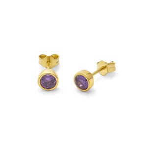 May include: A pair of gold stud earrings featuring round, bezel-set purple gemstones. The earrings have a classic design and are set against a white background. The earrings are a jewelry item.