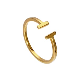 Könnte beinhalten: Ein polierter, goldfarbener offener Ring mit einem T-förmigen Design an beiden Enden der Ringschiene. Der Ring hat eine glatte, reflektierende Oberfläche und eine offene Struktur, die durchgehend ein sauberes, metallisches Finish aufweist.