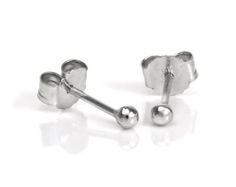 Op de afbeelding: Een paar kleine, zilverkleurige oorstekers. Elke oorbel heeft een ronde, kogelvormige knop die met een vlindersluiting aan een pin is bevestigd. De oorbellen worden op een wit oppervlak getoond.