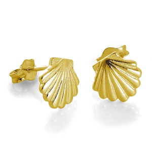 May include: A pair of gold-colored seashell stud earrings. The earrings are detailed with textured ridges and have post-and-clutch backings. The earrings are displayed on a white background.