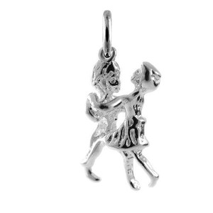 Peut inclure: Un pendentif en métal argenté brillant représentant deux silhouettes en train de danser. Les personnages sont reliés par la taille et les bras, l'un d'eux portant une jupe. Un petit anneau circulaire est fixé au sommet pour le suspendre.