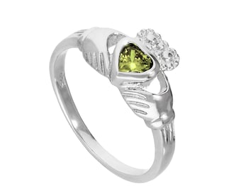 May include: A silver Claddagh ring featuring a heart-shaped green gemstone, held by two hands, and topped with a crown. The ring is a symbol of love, loyalty, and friendship. The ring is a classic design.