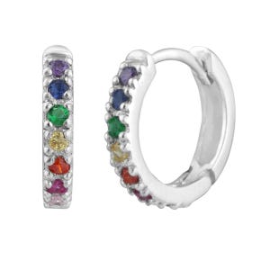 Puede incluir: Dos pendientes de aro plateados, cada uno adornado con una fila de gemas coloridas. Las gemas están dispuestas en un patrón de arcoíris, con colores que incluyen púrpura, azul, verde, amarillo, rojo y rosa. Los pendientes están sobre un fondo blanco.