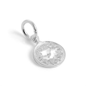 May include: A silver-toned metal charm shaped like a circular clock face with raised numerals and central hands. The charm features a textured finish and includes a small circular jump ring at the top for attachment to a chain or bracelet.
