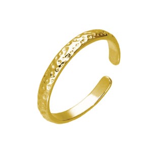 Pode incluir: Um anel de dedo do pé aberto dourado com uma textura martelada. O anel tem um design simples e elegante e é aberto na parte inferior, permitindo um ajuste ajustável. O anel é mostrado em um fundo branco.